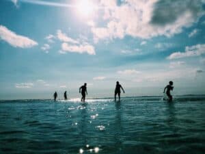 Children playing and splashing in the ocean under a sunny sky.