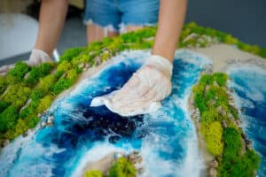 Hands cleaning a detailed ocean and river ecosystem model for marine protection.